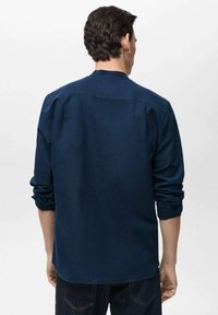Navy blue, long-sleeve shirt with a relaxed fit. Features a round collar, rolled cuffs, and a smooth texture, shown from the back.