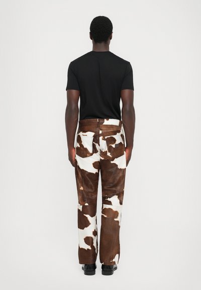 Pantaloni cu imprimeu de vacă maro și alb, cu croială dreaptă, material texturat și design cu cinci buzunare. Asortați cu un T-shirt negru ajustat.