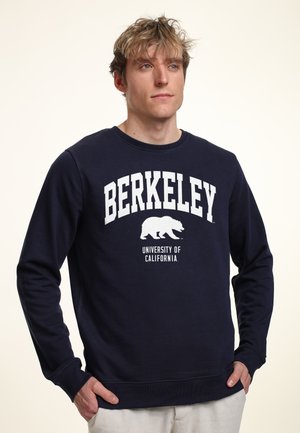 Felpa blu navy in cotone, con collo a girocollo, polsini a coste e un design con la scritta "BERKELEY" e un grafiche di un orso in bianco.