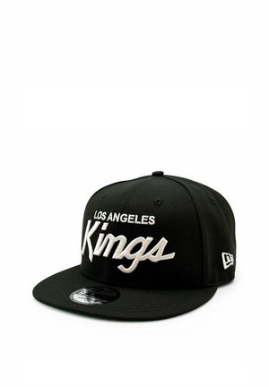Musta snapback-lippis, jossa valkoinen kirjailtu teksti "Los Angeles Kings" ja New Era -logo sivussa, asetettuna valkoiselle taustalle.