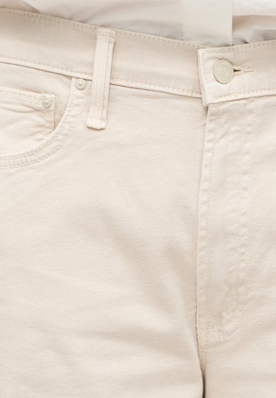 Μπεζ βαμβακερά τζιν με λεία υφή, διαθέτουν κλασικό σχεδιασμό με πέντε τσέπες, κλείσιμο με κουμπί και διακριτικές λεπτομέρειες ραφής.