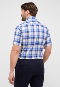 Camicia a maniche corte a quadri in blu, giallo e bianco. Presenta un colletto a punta e un yoke posteriore, con un tessuto morbido e una vestibilità comoda.