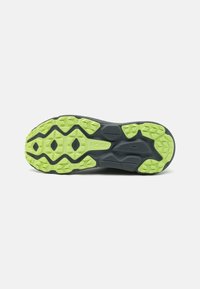 Semelle de chaussure de trail avec une semelle en caoutchouc noir et vert vif, dotée de crampons multidirectionnels pour une meilleure traction et durabilité. Logo HOKA visible.
