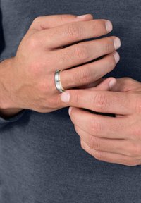 Silver and gold band ring, featuring a brushed silver finish with a polished gold accent, worn on a hand with natural fingernails.