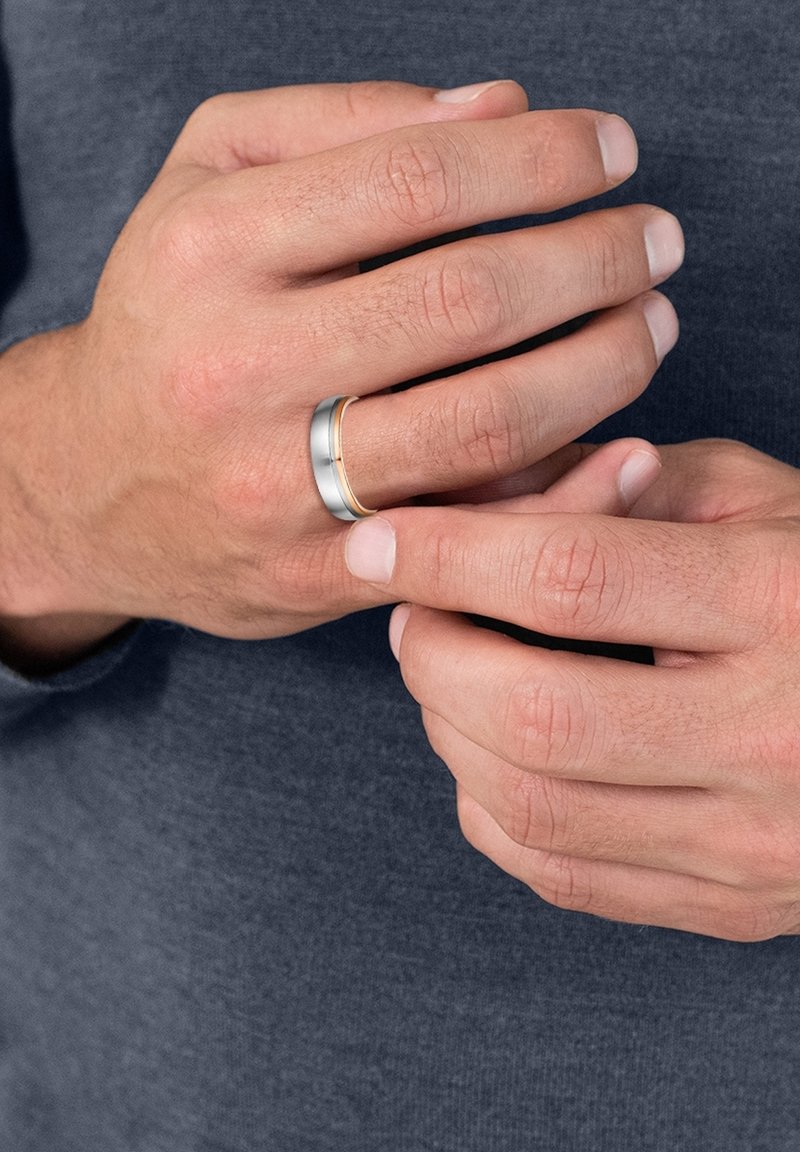 Silver and gold band ring, featuring a brushed silver finish with a polished gold accent, worn on a hand with natural fingernails.