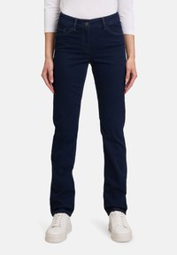 Jean slim-fit bleu foncé en denim doux, avec des poches avant, une fermeture à bouton, et des accents de couture subtils.