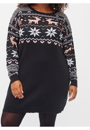 Persona que lleva un vestido negro de manga larga con un reno rosa, copos de nieve blancos y patrones geométricos en el pecho y las mangas.