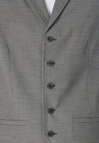 Muška blazer jakna u crno-bijelom hounds-tooth uzorku. Ima šest smeškastih dugmadi, urezane reveri i bočne džepove. Teksturirana tkanina.