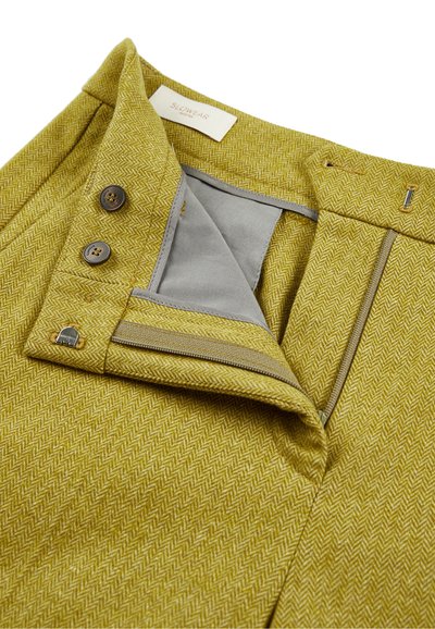 Geel visgraat stof rok tailleband met twee bruine knopen, metalen haak sluiting, en een beige rits die gedeeltelijk geopend is en grijze voering toont.