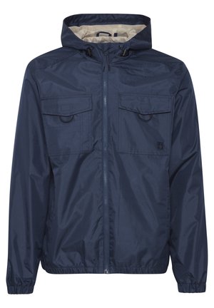 Námornícky modrý windbreaker s kapucňou, plným zipsom, dvoma náprsními vreckami, elastickými manžetami a vnútorným podšívkou v kontrastnej svetlej farbe.