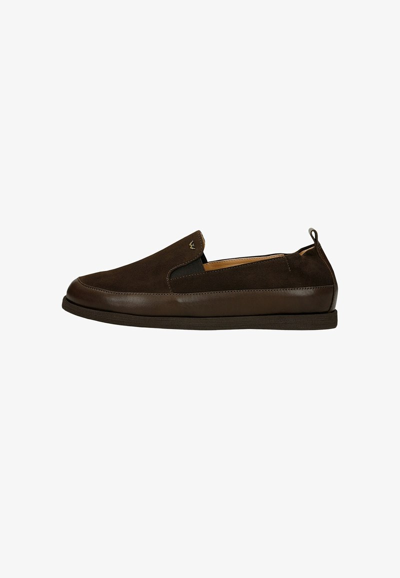 Chaussure en suède et cuir marron foncé facile à enfiler, avec petit talon et panneaux latéraux élastiques sur fond blanc.