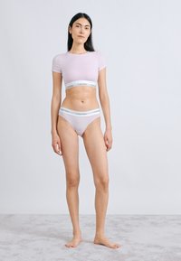 Ροζ ανοιχτού χρώματος αμάνικο crop top χωρίς ραφές και ταιριαστό εσώρουχο χαμηλής μέσης με λευκή ζώνη Calvin Klein, απαλό ύφασμα, εφαρμοστή σχεδίαση και χωρίς σχέδια.