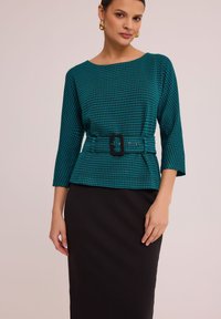 Top w morskim wzorze w jodełkę z rękawami o długości trzech czwartej i dopasowanym fasonie, z czarnym paskiem i okrągłym dekoltem, zestawiony z czarną spódnicą.
