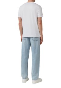 Weißes Baumwoll-T-Shirt mit Rundhalsausschnitt, kombiniert mit hellblauen Jeans. Weiße Sneaker runden das Outfit ab. Einfaches, lässiges Design.