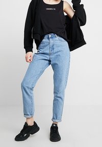 Ljusblå, högmidjade jeans med smalad ben och uppvikta nederkanter, kombinerat med en svart linne och svarta träningstövlar.