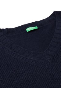 Marineblauer Strickpullover mit V-Ausschnitt. Verfügt über einen gerippten Kragen und Saum, hergestellt aus einem weichen Stoff. Grünes Etikett mit der Aufschrift "United Colors of Benetton."