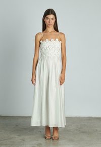 Witte maxi-jurk met een aansluitend kanten lijfje en dunne bandjes, die onder de taille doorvloeit met een gladde, lichte stof.