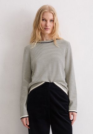 Striped long-sleeve shirt in cream and navy, featuring a round neckline and ribbed cuffs, paired with black corduroy trousers.