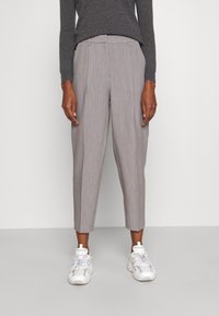 Szare spodnie w prążki o dopasowanym kroju, z mid-rise talią, zwężanymi nogawkami i plisowanymi detalami, zestawione z białymi trampkami.