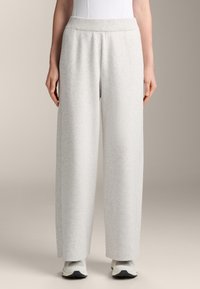 Hellgraue, weit geschnittene Sweatpants mit elastischem Bund, weichem Material und dezenten Nahtdetails an den Seiten. Eignen sich ideal für die Freizeit.