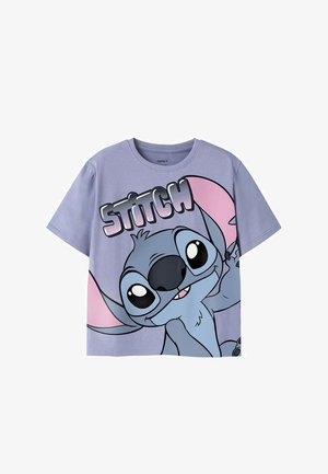 Chemise lilas à manches courtes avec un grand personnage de dessin animé Stitch aux oreilles roses et le mot "STITCH" en lettres majuscules au-dessus.