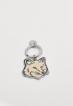 Keychain featuring a fox head design in light beige enamel with black outlines, attached to a silver metal ring with a small tag.