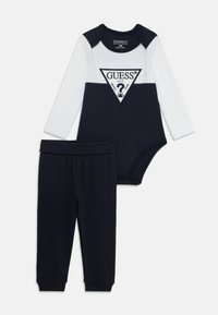 Body à manches longues bleu marine et blanc avec logo triangulaire, associé à un pantalon bleu marine assorti. Matière en coton, coupe confortable, taille élastique.