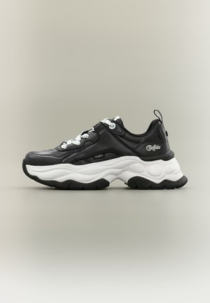 Zapatilla deportiva gruesa en blanco y negro con suela gruesa y texturizada y cordones blancos, con la marca "Buffalo" en el lateral y el talón, mostrada en vista lateral.