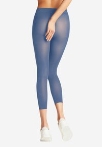 Leggings blu semi-trasparenti con vita a media altezza, lunghezza cropped, texture liscia, abbinate a scarpe da ginnastica bianche.