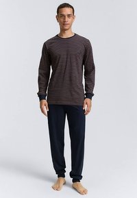 Bluză de pijama cu mâneci lungi, în dungi albastre închise și burgundy, asortată cu pantaloni uni bleumarin. Material moale, cu mansete și guler striate.