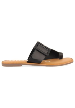 Las sandalias planas negras cuentan con una correa ancha con una hebilla cuadrada, una plantilla marrón y una suela de goma texturizada. El diseño es minimalista y moderno.