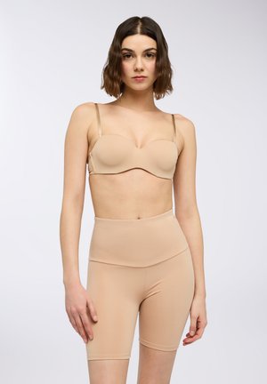 Reggiseno nude senza spalline con coppe lisce e sottili spalline lucide, abbinato a pantaloni corti nude a vita alta realizzati in tessuto elasticizzato.