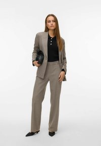 Helehall hall ülikond kohandatud bleiseri ja laiade pükstega, millele on lisatud must polosärk ja must käekott, millel on teravate otstega mustad kontsaga kingad.