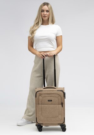 Valigia rigida in tessuto beige con una sottile texture, scomparti con zip, manico telescopico nero e quattro ruote per la mobilità.