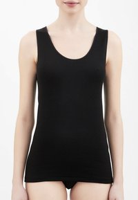 Top senza maniche nero realizzato in un tessuto liscio, con un colletto arrotondato e un design attillato che si ferma sopra i fianchi.