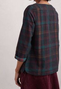 Camicia a quadri in tonalità scure di teal, marrone e bordeaux, con scollatura tonda, maniche a tre quarti e spacchi laterali.