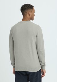 Hellgrauer Pullover, Strickmaterial, Rundhalsausschnitt, lange Ärmel, gerippte Bündchen und Saum, glatte Textur, von hinten gezeigt.
