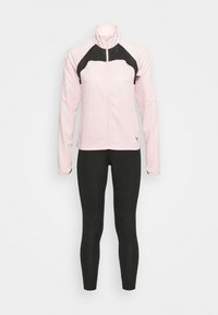 Helle rosa Zip-Jacke mit schwarzen Schulterakzenten, langen Ärmeln und hohem Kragen, kombiniert mit schwarzen, eng anliegenden Leggings.