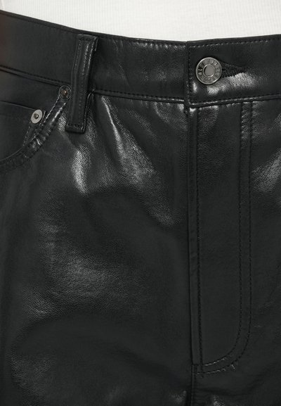 Schwarze Lederhose mit glänzender Textur, genähten Details, Metallknopfverschluss und Vordertasche mit Niete.