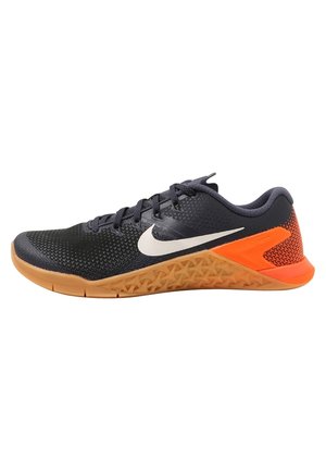 Sort og orange Nike løbesko med hvid Swoosh-logo, tekstureret sål og snørebånd, vist fra siden på hvid baggrund.