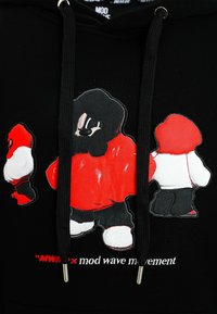 Tres figuras estilizadas con sudaderas rojas, negras y blancas sobre una tela negra, con el texto "MWM x mod wave movement" debajo.