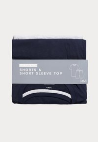 Conjunto de pantalones cortos azul marino y camiseta de manga corta, de mezcla de algodón, cuidadosamente doblado con una etiqueta gris que presenta detalles del producto e íconos de los artículos incluidos.