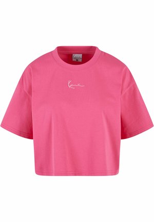 Růžové zkrácené tričko vyrobené z bavlny. Má kulatý výstřih a krátké rukávy. Výrazný detail: bílá podpisová grafika na hrudi.