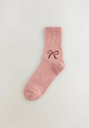 Rozā kokvilnas zeķe ar ribotu malu, kurā ir tumši rozā loku grafika. Mīksta tekstūra un potītes augstuma dizains.