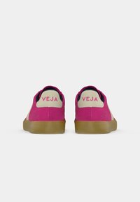 Pink suede sneakers with a beige upper section and gum rubber sole. Features branding on the heel and a rounded toe design.