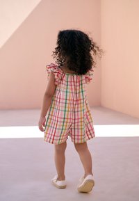 Colorful plaid romper with ruffled sleeves, featuring shades of pink, green, and yellow. Seen from behind, paired with white shoes.