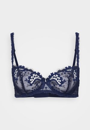 Soutien-gorge en dentelle bleu marine avec un tissu en mesh transparent, broderie florale, bretelles réglables et un détail en nœud au centre. Présente un soutien-gorge avec armatures.