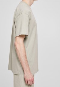 Jasno beżowa koszulka z krótkim rękawem w luźnym kroju, wykonana z miękkiej bawełny. Posiada klasyczny okrągły dekolt i prosty dół.