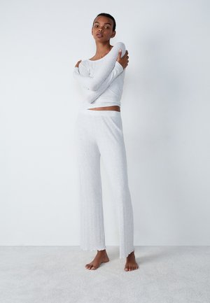 Completo loungewear grigio chiaro composto da una maglietta a maniche lunghe aderente e pantaloni wide-leg a trama con orlo scallop. Materiale morbido.