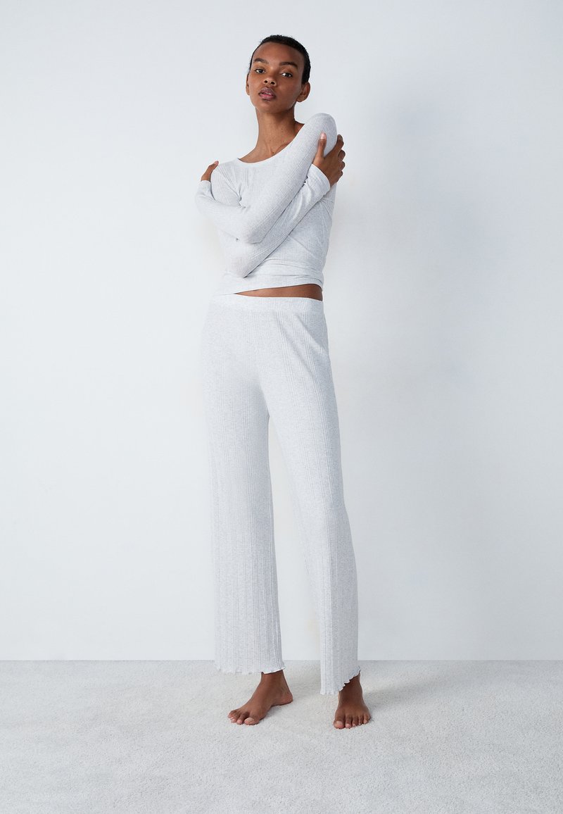 Lichtgrijze loungewear-set met een getailleerde lange mouw top en getextureerde wijde broek met een golvende zoom. Zacht materiaal.